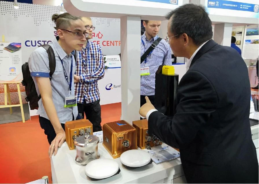 Visitors discussing the iPos navigation equipment displayed on the Shanghai exhibition stand in 2019